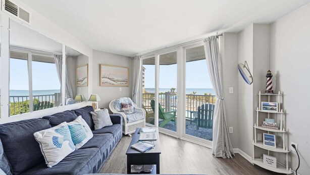 A modern living room with a sofa, armchairs, a coffee table, and a bookshelf. - Oceanfront condo with shared pool, shared sauna and beach access (North Topsail Beach)