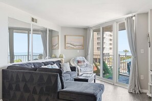 Ein Wohnzimmer mit einer Couch, einem Sessel und einem Balkon mit Blick.