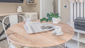 A round wooden table with a newspaper, a white cup, and a saucer. There is a potted plant on the table. - Thea-historical center Monza (Monza)