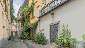 A narrow alleyway with buildings on either side, some with balconies and greenery. - Thea-historical center Monza (Monza)