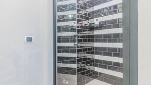A modern bathroom with a glass shower enclosure and a tiled wall. - Thea-historical center Monza (Monza)