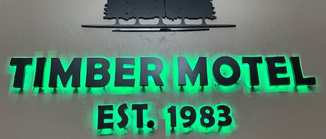 A sign for Timber Motel with a forest silhouette and the establishment year 1983.