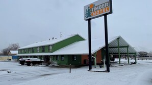 A motel with a green exterior and a covered parking area. - Timber Motel (Clinton)
