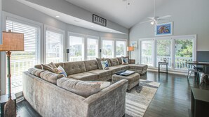 Ein geräumiges Wohnzimmer mit einer großen Eckcouch, einem Deckenventilator und einem Schild mit der Aufschrift 'BEACH'.