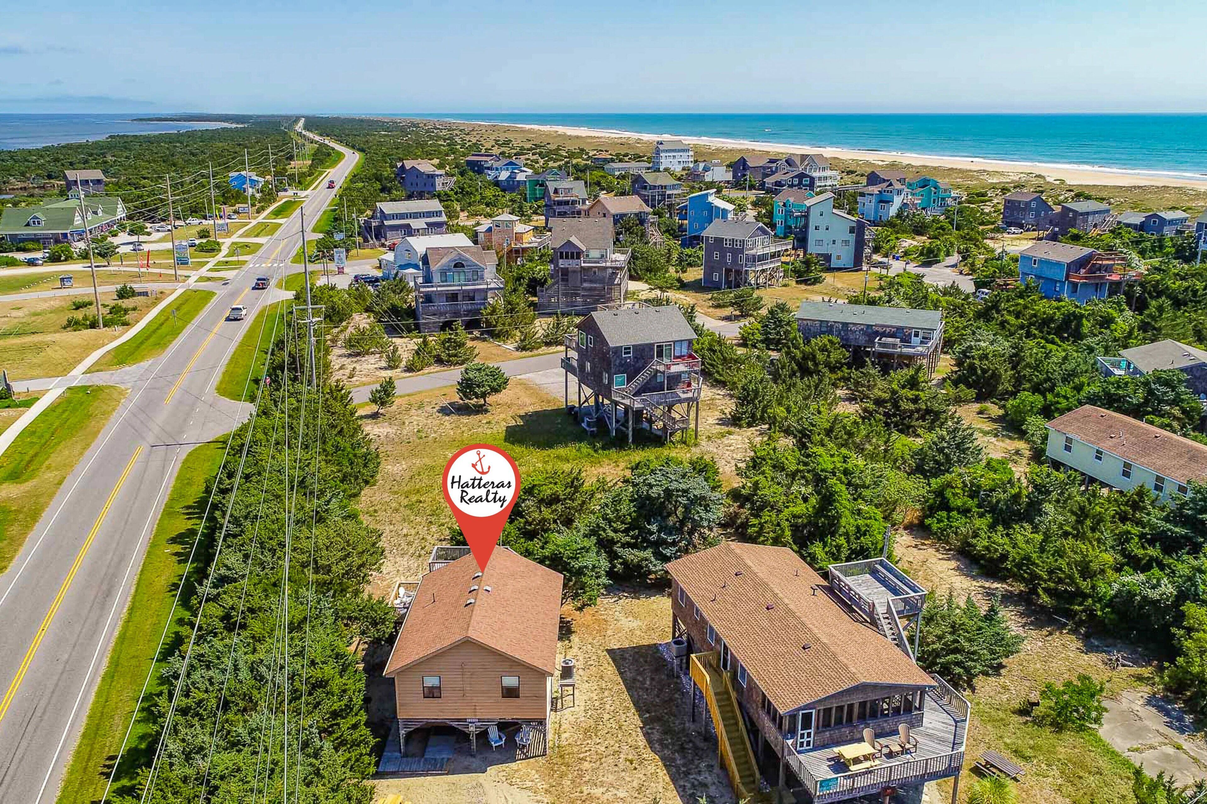 Vista aérea de una zona residencial costera con casas, una carretera y una playa.