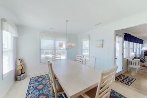 Een eetruimte met een houten tafel en stoelen, een tapijt met een patroon en een beeld.
