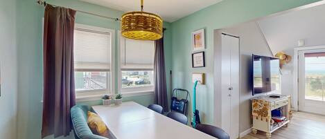 A dining area with a white table, blue chairs, and a wicker chandelier.