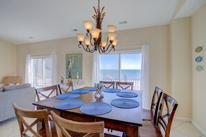 Un comedor con una mesa de madera, individuales azules y una araña.
