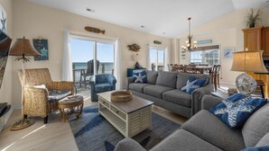 A spacious living room with a large sofa, two armchairs, a coffee table, and a dining area with a table and chairs. - Oceanfront home with great views, central AC, washer/dryer, beach access (North Topsail Beach)