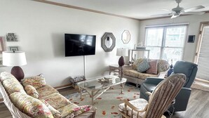 A living room with a sofa, armchair, and a coffee table. - Fantastic house with WiFi, central AC, and private washer/dryer - steps to beach (Holden Beach)
