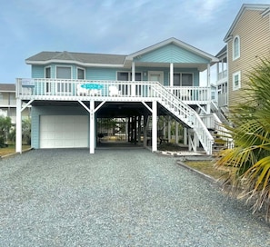 A two-story building with a covered entrance, a balcony, and a staircase leading to the upper level.