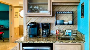 A compact kitchen with a built-in dishwasher, a coffee maker, and a shelf with kitchenware. - Oceanfront Retreat, Stunning Views, Renovated Spaces, Game Room with Pool Table (Avon)