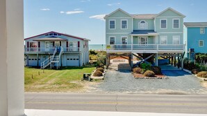 A two-story building with a covered walkway and a staircase leading to a second level. - Magnificent house with central AC, patio, deck, W/D & screened porch (Holden Beach)