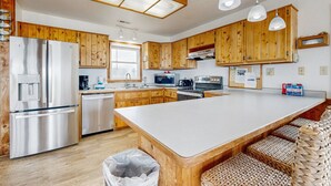 Une cuisine moderne avec des meubles en bois, des appareils en acier inoxydable et un îlot central doté de sièges.