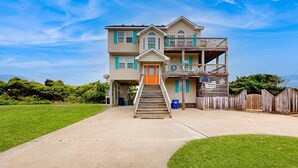 A two-story house with a front porch and a staircase leading to the door. - Inviting house with central AC, private pool, hot tub, ocean views, & W/D (Hatteras)