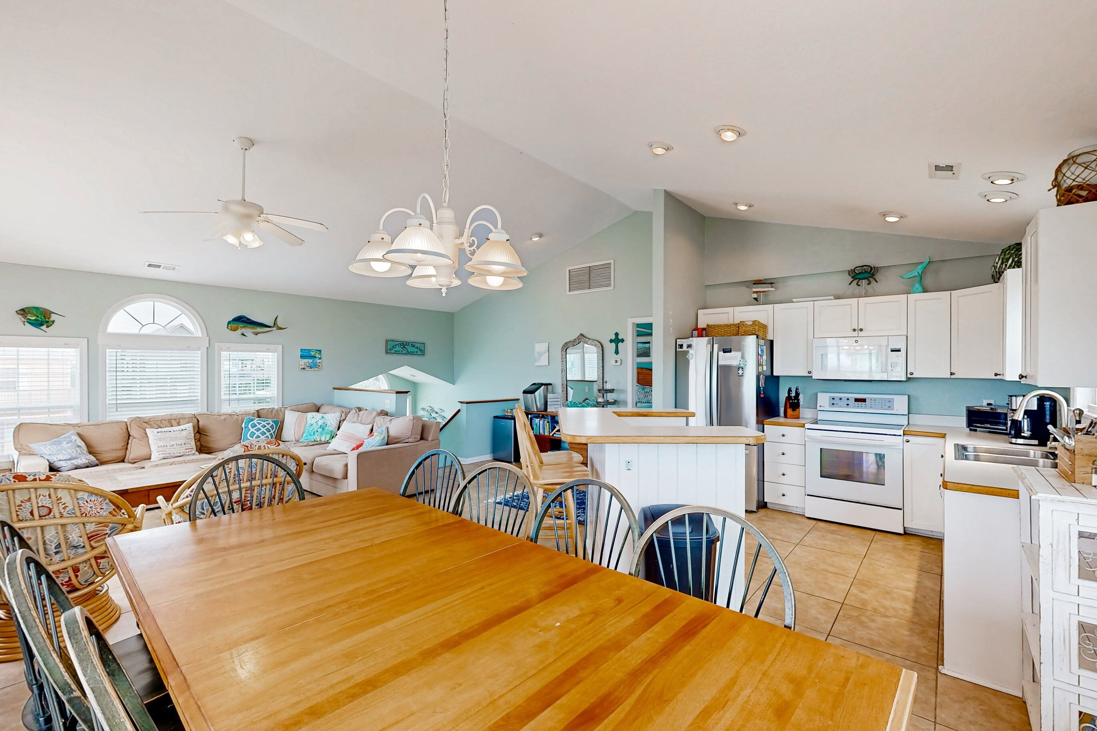 A spacious kitchen with white cabinets, a central island, and a dining area with a wooden table and chairs.