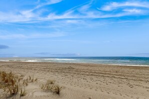 A beach with sand and sparse vegetation. - Fun-Filled Beachfront House w/Free WiFi, Private Washer/Dryer, AC, Patio, Deck (Holden Beach)