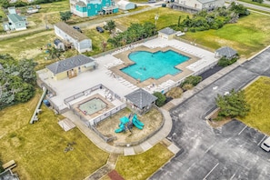 An aerial view of a residential area with a swimming pool, a playground, and a parking lot.