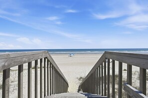 A wooden boardwalk leading to a beach with a clear sky.