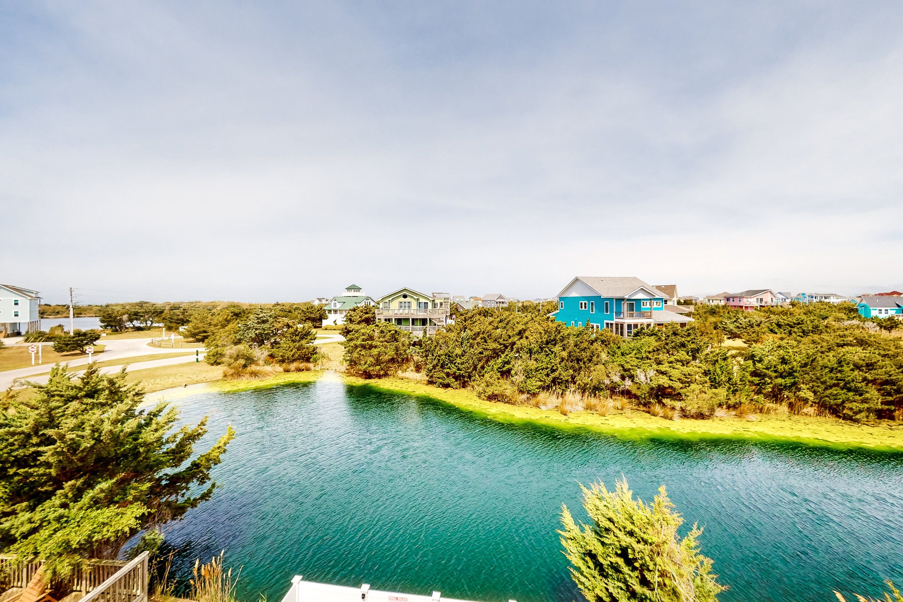 A residential area with a lake, houses, and a pathway.
