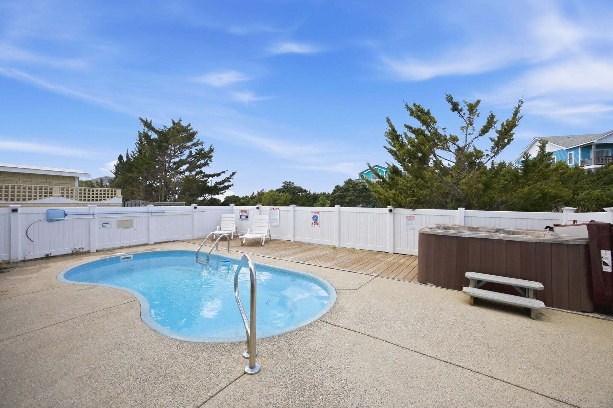 Un jardin avec une piscine, un jacuzzi et une terrasse en bois.