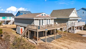 A beachfront house with a covered deck and a small boat shed. - Large and roomy house across from the beach with WiFi, W/D, central AC, and deck (Holden Beach)
