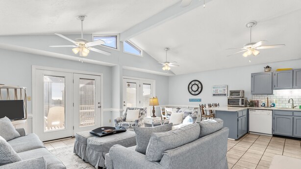 A spacious living room with a grey sofa set, a dining area, and a kitchen with grey cabinets and a white countertop. - Large and roomy house across from the beach with WiFi, W/D, central AC, and deck (Holden Beach)