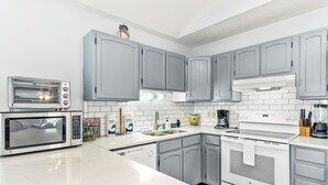 A modern kitchen with grey cabinets, a built-in oven, a microwave, and a dishwasher. - Large and roomy house across from the beach with WiFi, W/D, central AC, and deck (Holden Beach)