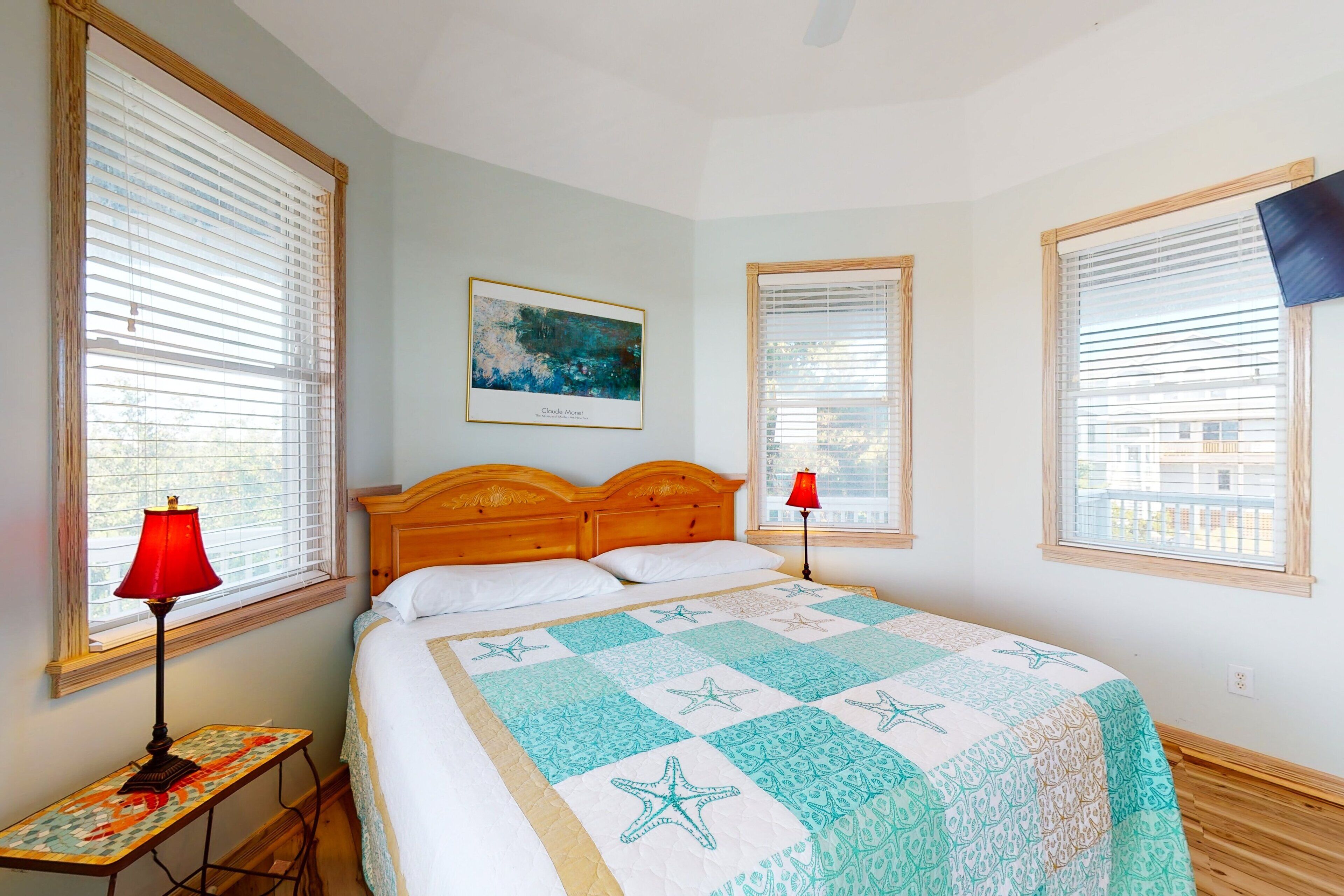 A bedroom with a bed, a nightstand, a lamp, and a painting on the wall.