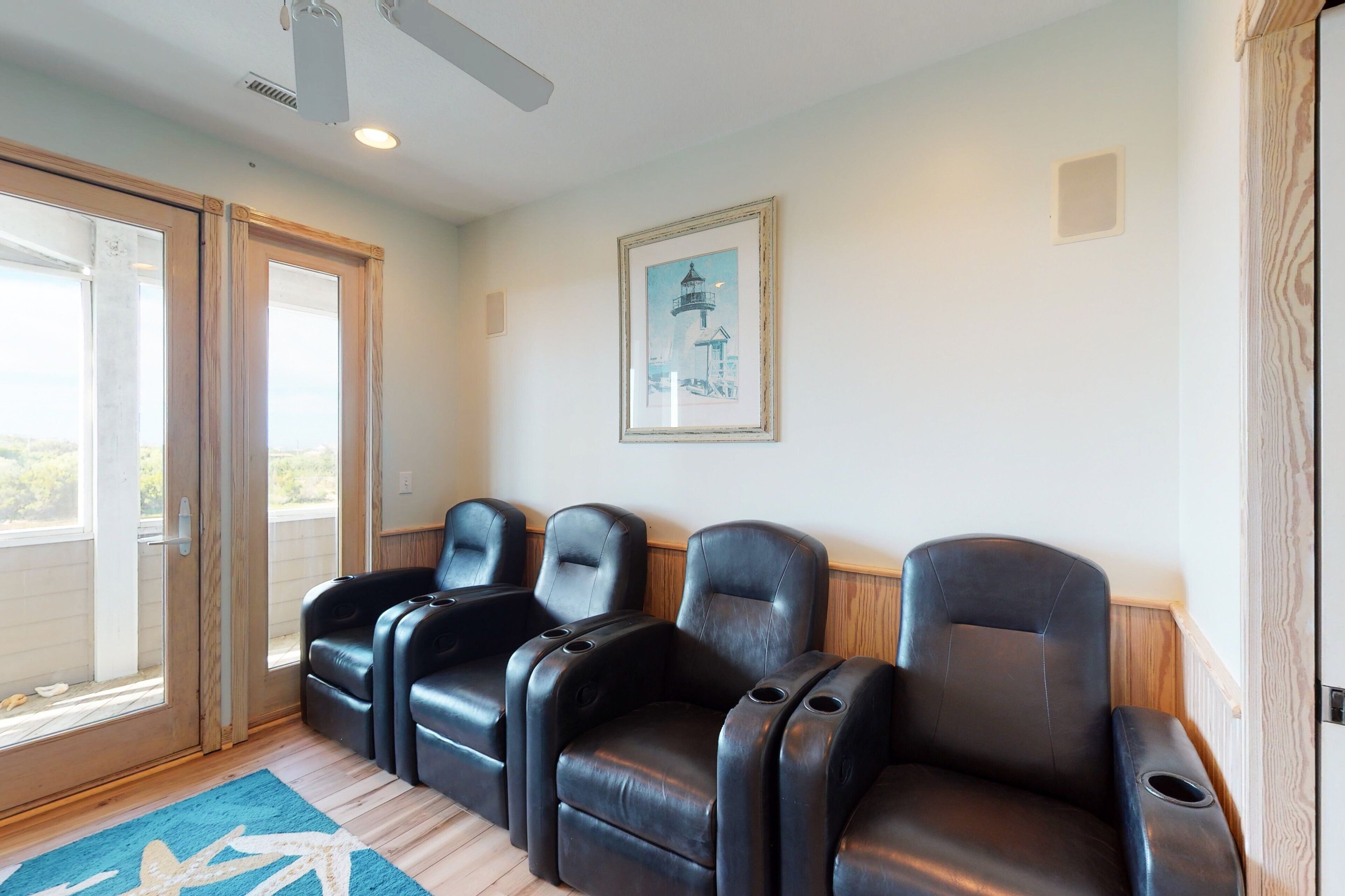 A room with three black leather recliners, a framed picture on the wall, and a door leading outside.