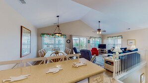 A spacious living area with a dining table, chairs, a sofa, and a TV. - Dog-friendly duplex in Surf City with beautiful ocean views — just steps from beach access! (Surf City)
