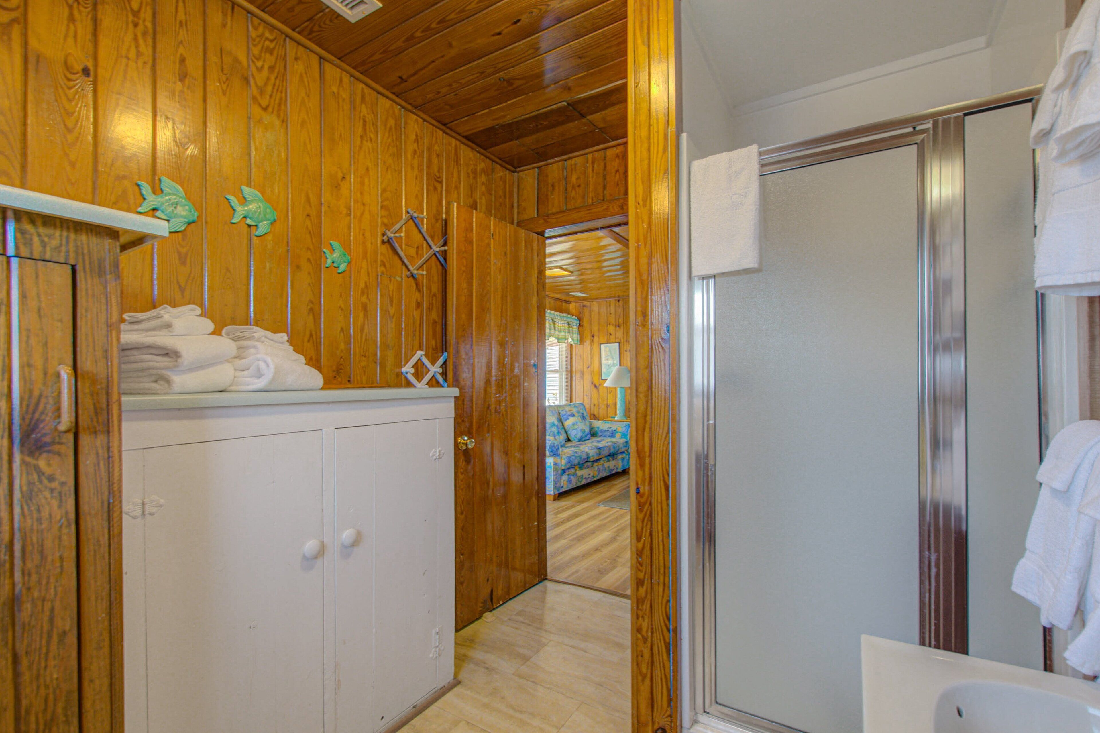 A wooden interior with a bathroom featuring a shower, a sink, and a towel rack.
