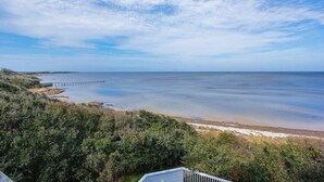 A coastal landscape with a pier extending into the water, surrounded by dense vegetation. - Waterfront house with private pool, hot tub, W/D, &vocean view (Buxton)