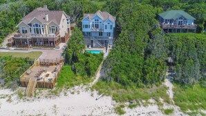 A large, multi-story house with a pool, surrounded by dense greenery and a sandy beach. - Waterfront house with private pool, hot tub, W/D, &vocean view (Buxton)