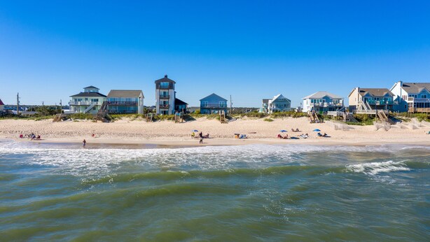 Une propriété située en bord de mer, comprenant plusieurs maisons, une plage de sable et donnant sur l’océan.