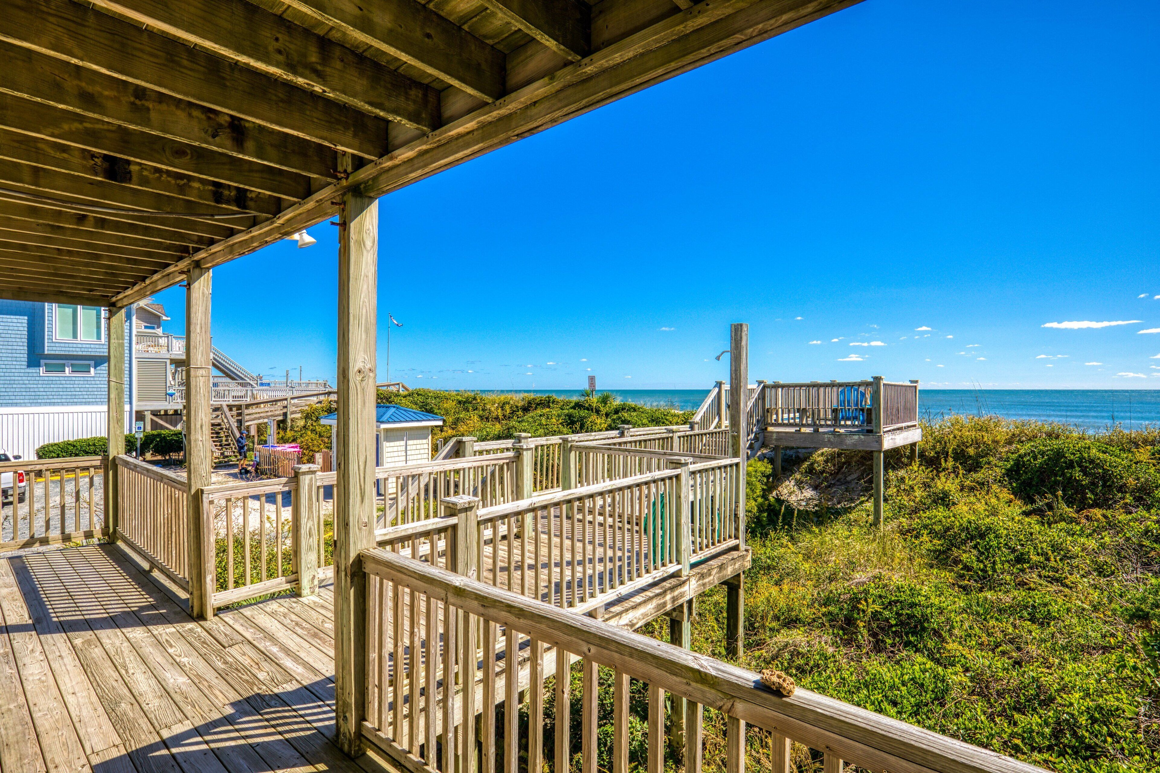 A wooden deck with a view of the ocean and beach vegetation.