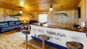 Un interior de fusta amb un sofà de pell, un taulell amb la inscripció "BIG TAHUNA" i peixos penjats a les parets.
