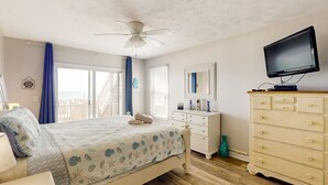 Een slaapkamer met een bed, een dressoir, een televisie en uitzicht op de omgeving.