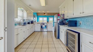 A kitchen with white cabinets, a blue backsplash, a central island, and a built-in oven. - HB93 Holden Friends - 2nd row, 3 bedroom, NEW private pool (Holden Beach)