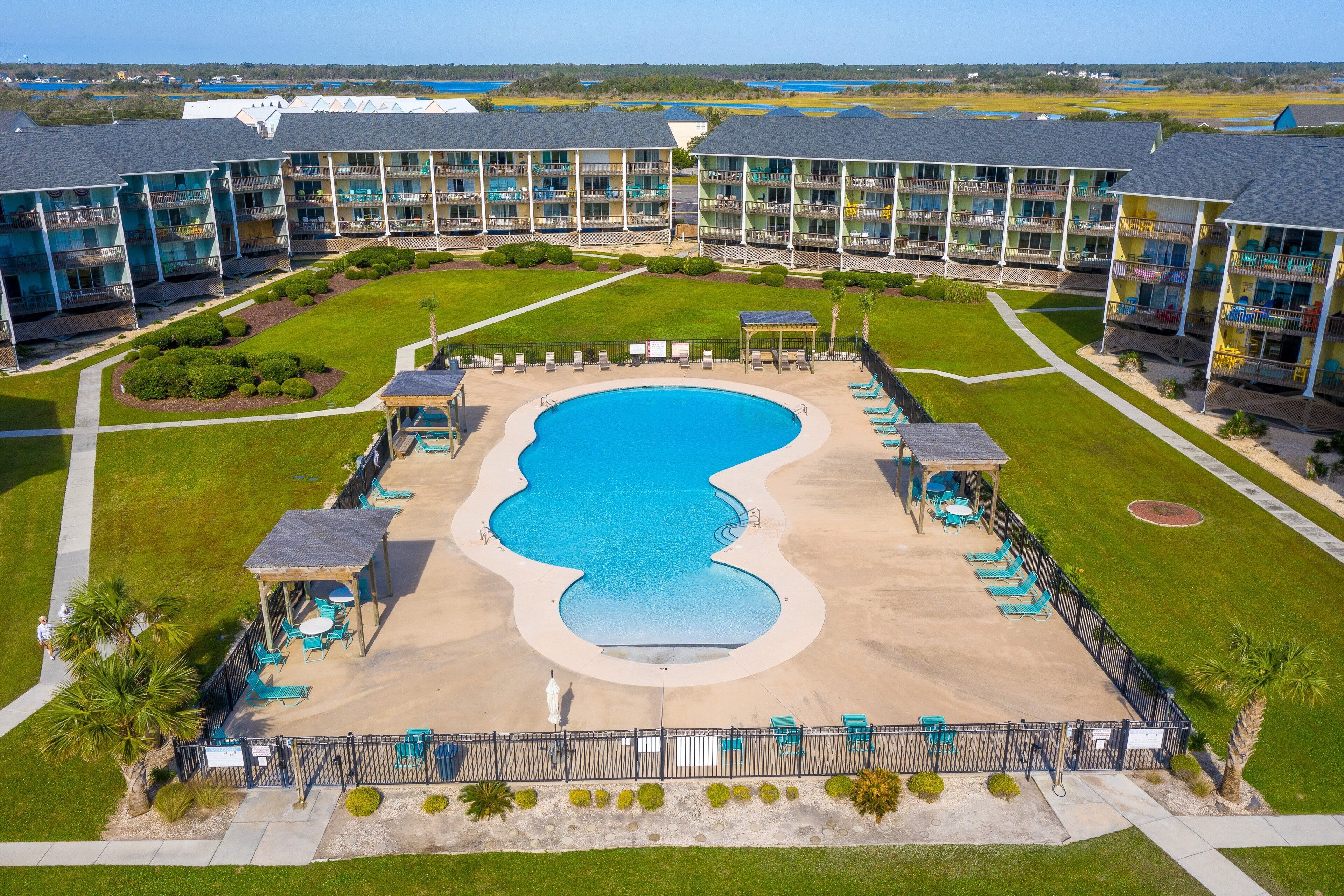 A resort with a central swimming pool, multiple balconies, and outdoor seating areas.