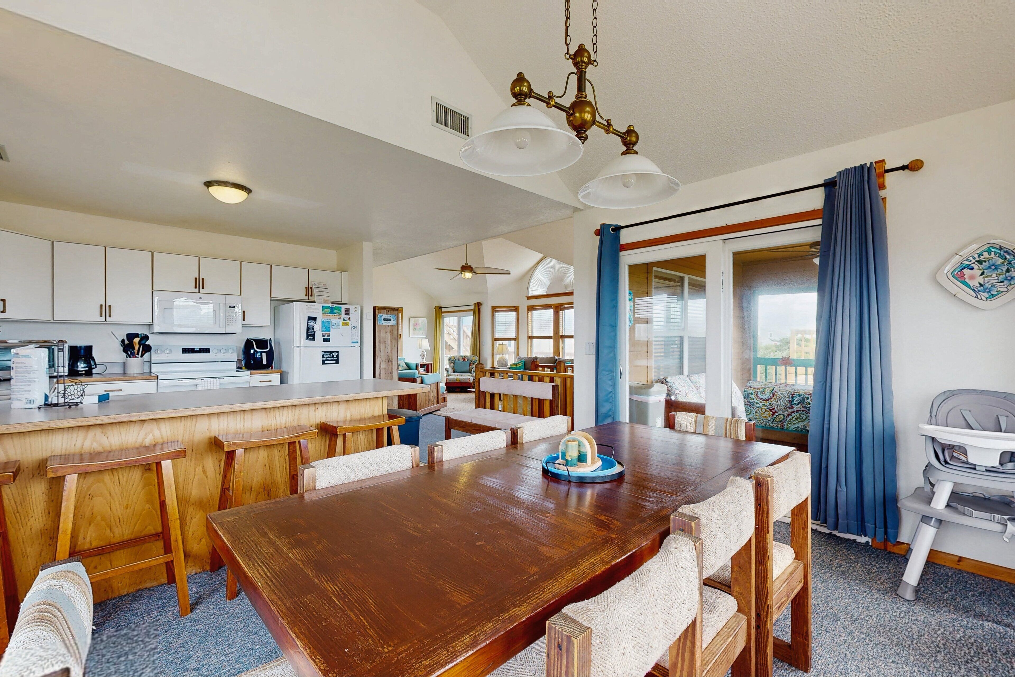 A spacious kitchen with white cabinets, a wooden dining table, and a baby high chair.