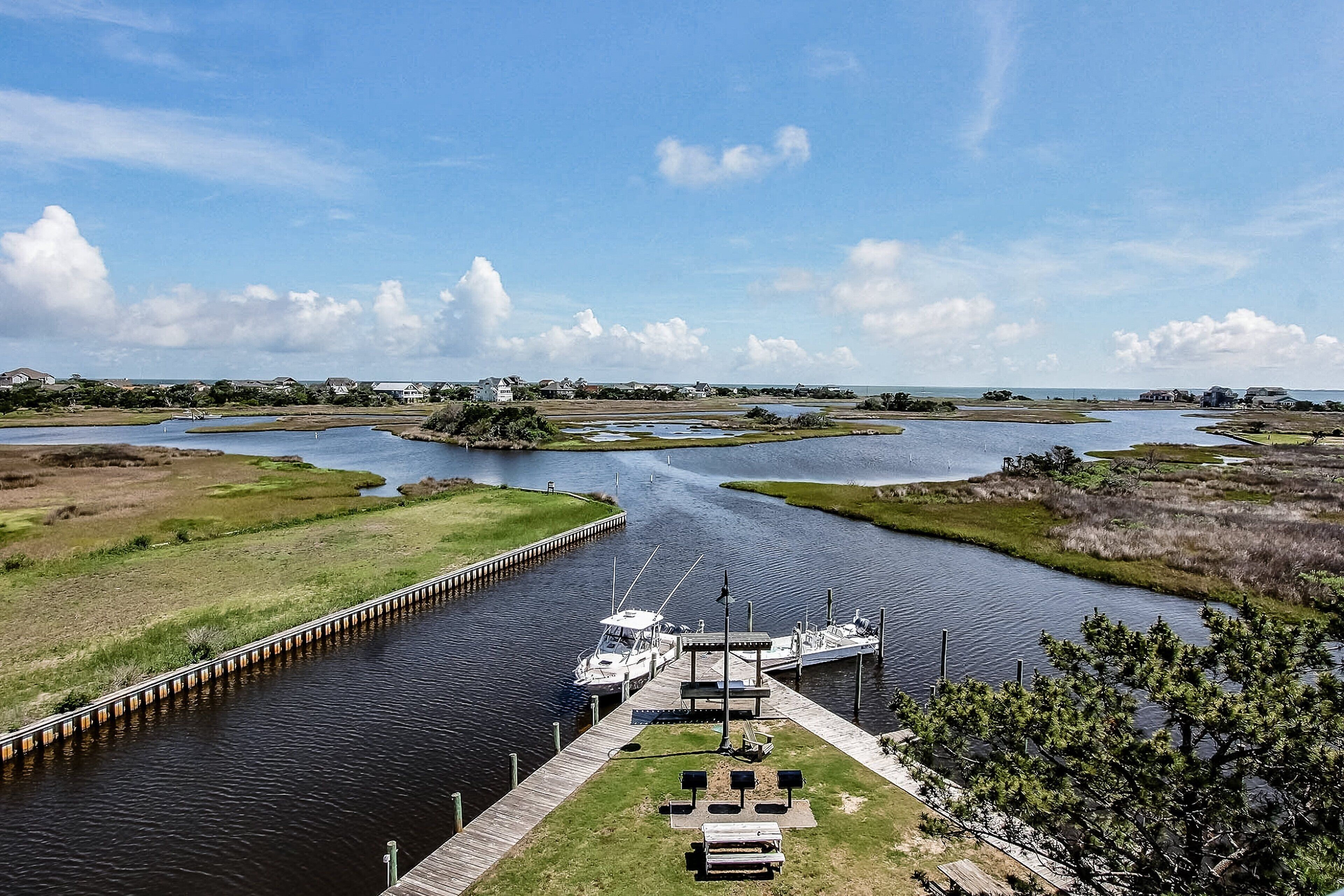 A marina with boats docked, a wooden pier, and a grassy area with a small island.