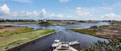 A marina with boats docked, a wooden pier, and a grassy area with a small island.
