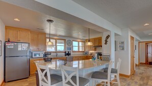 A spacious kitchen with wooden cabinets, a central island with bar stools, and pendant lighting. - Oceanfront home with hot tub, WiFi, ocean view, central AC, & washer/dryer (Avon)