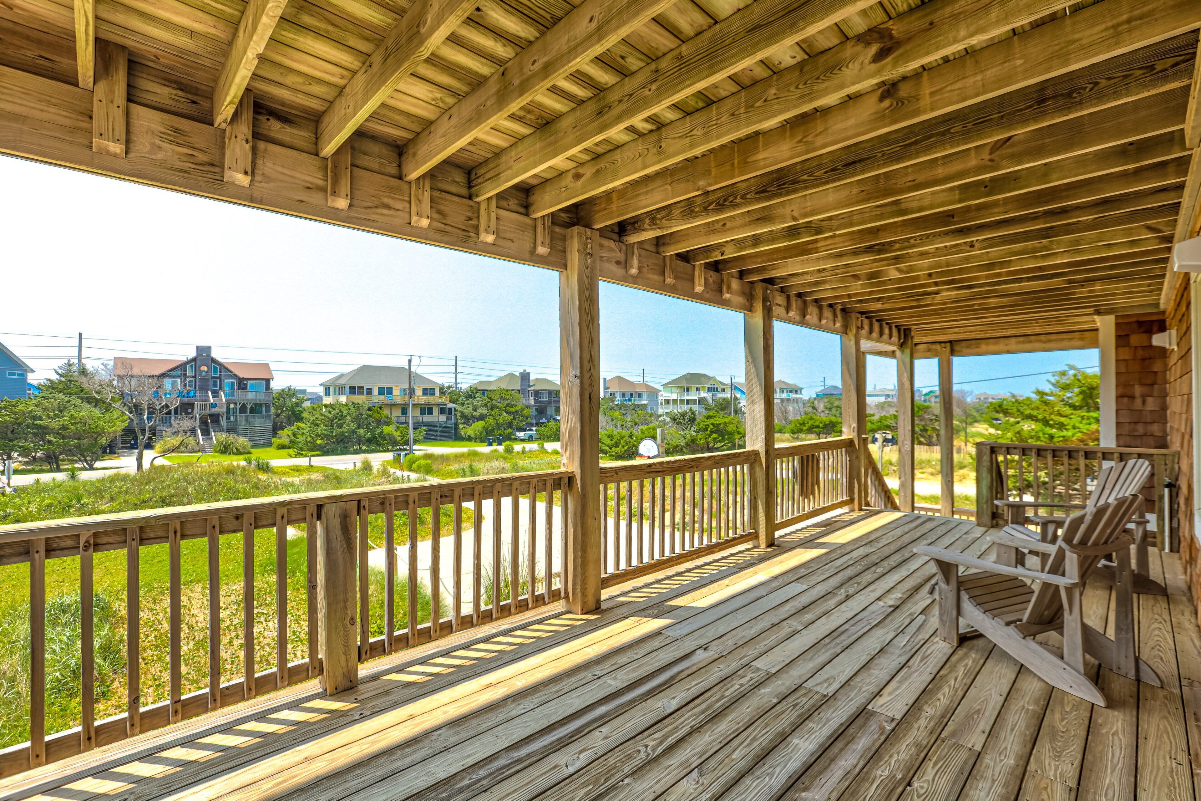 A wooden deck with a railing, a wooden chair, and a view of houses in the background.
