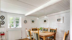 A dining area with a wooden table and chairs, a window with a view, and a radiator. - 5 Star Holiday Home in Orsted (Ørsted)