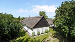 A traditional thatched-roof house with a white exterior, surrounded by lush greenery and trees. - 5 Star Holiday Home in Orsted (Ørsted)