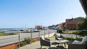 A wooden deck with outdoor furniture overlooking a marina and a road. - 4 Star Holiday Home in Allinge (Allinge)