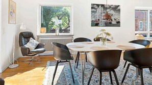 A modern dining area with a round table, black chairs, and a view of a cityscape through large windows. - 4 Star Holiday Home in Allinge (Allinge)