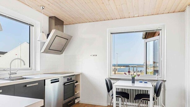 A modern kitchen with a built-in oven, a sink, and a dining area with a table and chairs. - 4 Star Holiday Home in Allinge (Allinge)